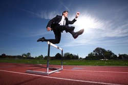 Businessman jumping over hurdle