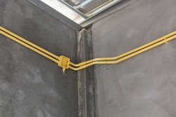 Yellow PVC pipes for electrical boxes and wires buried on concrete wall background