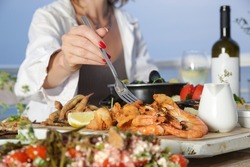 Young woman enjoying seafood platter during the sunset in the beach restaurant	