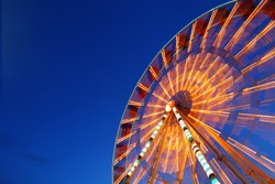 Ferris wheel and rollercoaster in motion at amusement park at night