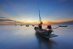 Silhouette of small fishing boats parked on a quiet sea. long movement with sunrise at Chao Lao Beach, Chanthaburi, Thailand