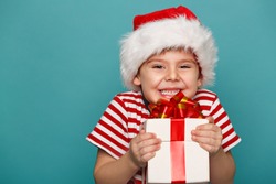 Smiling  funny child in Santa red hat holding Christmas gift in hand. Christmas concept.