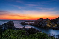 Aerial seascape of natural stone arch and sea against twilight sky at dusk in Ko Man Klang, Rayong, Thailand. Famous travel destination and summer holiday vacation in tropical country, Siam.