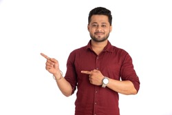 Portrait of a successful cheerful young man pointing and presenting something with hand or finger with a happy smiling face.
