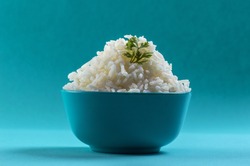 Cooked plain white basmati rice with corriander in a blue bowl on blue background