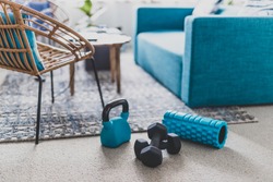 home gym and exercising indoor concept, set of fitness gear on living room carpet next to the couch in a living room shot at shallow depth of field