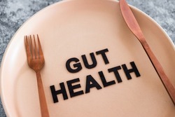 gut health text on dining plate with fork and knife, healthy nutrition and scientific research about the microbiome	