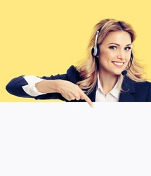 Call center. Customer support service female phone operator or sales agent in headset, grey confident suit pointing at mock up signboard with copy space for text, isolated over yellow background.