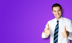 Portrait of amazed businessman in confident white shirt and tie, making thumbs up like hand sign gesture, over violet purple background. Happy smiling man gesturing. Success in business. Awesome awe