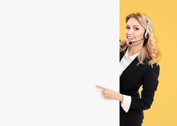 Call center. Customer support service female phone operator or sales agent in headset, confident suit standing behind signboard with copy space area for text, isolated on yellow background