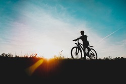 happy boy on bike ride in sunset nature