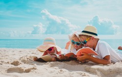 happy kids -boy and girls- read books on beach, summer reading on vacation