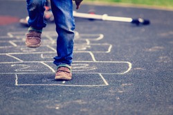 kid playing hopscotch on playground outdoors, children outdoor activities