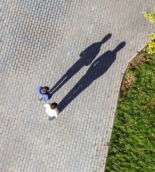 Silhouette of a two men casting a long shadow on a cobble stone road