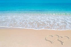turquoise water and golden sand in Sardinia with two hearts drawn in the sand