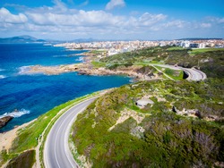 Winding coastal road to Alghero seen from above. Sardinia, Italy