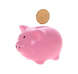 Piggy bank style money box with coins falling into slot isolated on a white studio background