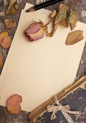 Dry rose and old book on a wooden background with space for information