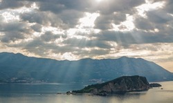 Landscape aerial view of the bay of the old historical city of Budva, mountains and forests of Montenegro, on the background of a dramatic sky and Sveti Nikola island