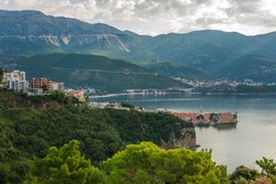Landscape aerial view of the bay of the old historical city of Budva, mountains and forests of Montenegro, on the background of a dramatic sky