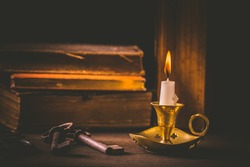 Pile of old antique books with candle and old rusty keys in vintage style on wooden black background