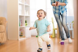 Baby boy running in the living room with his mother