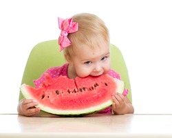 Little kid girl eating watermelon at table isolated on white background