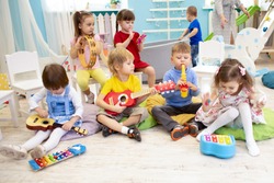 Kids learning musical instruments on lesson in kindergarten or preschool