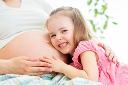 child girl listening pregnant mother's belly