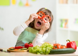 kid girl having fun with food vegetables at kitchen