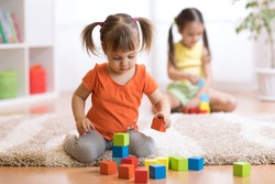 Children toddlers girls play toys at home, kindergarten or nursery.