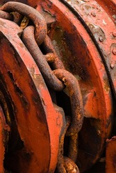 Strong rusty anchor chain on red metal winder