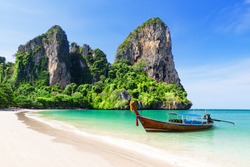 Thai traditional wooden longtail boat and beautiful sand Railay Beach in Krabi province. Ao Nang, Thailand.
