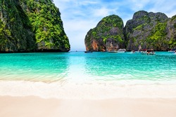 Beautiful beach with thai traditional wooden longtail boat and blue sky in Maya bay, Thailand. Vacation holidays summer background. View of nice tropical beach in Maya bay near Phuket in Thailand. 
