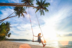 Asian girl on swing in Koh Kood island with coconut and beach background, trat, Thailand