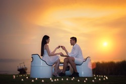 Asian boyfriend and girlfriend take diner with romantic sea, beach, candle and sunset in valentines day in tropical resort