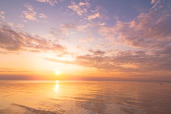 Calm sea with sunset sky and sun through the clouds over. Meditation ocean and sky background. Tranquil seascape. Horizon over the water.