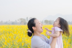 Asian mother and child having fun in flower field