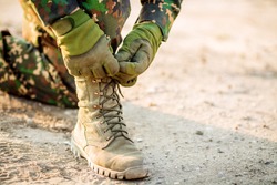 rangers boots and hands tying bootlaces in desert