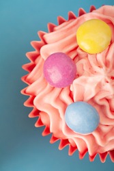 Still life of colorful decorative cupcake for children party on blue background space, interior. Sugar sweet treat baking, dessert eating, unhealthy food cooking, home kitchen activities for kids.
