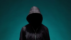 Portrait of computer hacker in hoodie. Obscured dark face. Data thief, internet fraud, darknet and cyber security .