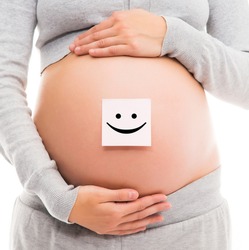 Belly of a young pregnant woman with a white sticker and a smiley on it