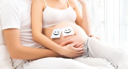 Close-up picture of man and woman awaiting a baby. Male hands on a pregnant belly. 