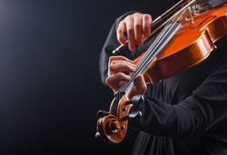 Playing the violin. Musical instrument with performer hands on dark background