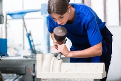 woman Stonemason carving pillar out of stone in her workshop
