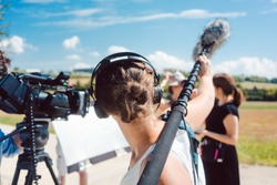 Woman holding microphone on a boom during video production capturing audio