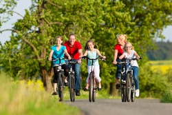 Family with three girls having a weekend excursion on their bikes or bicycles on a summer day in beautiful landscape