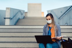 Student woman sitting on empty stairs of university campus working