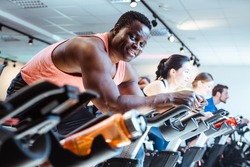 African man and friends exercising on fitness bike in gym