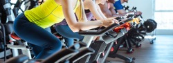 Very fit Caucasian woman and her friends on fitness bike in gym